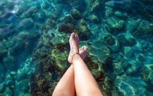 Ibiza girl legs at Portinatx beach clear water