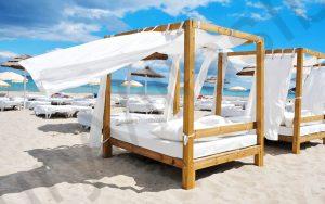 detail of some beds and sunloungers in a beach club in a white sand beach in Ibiza, Spain